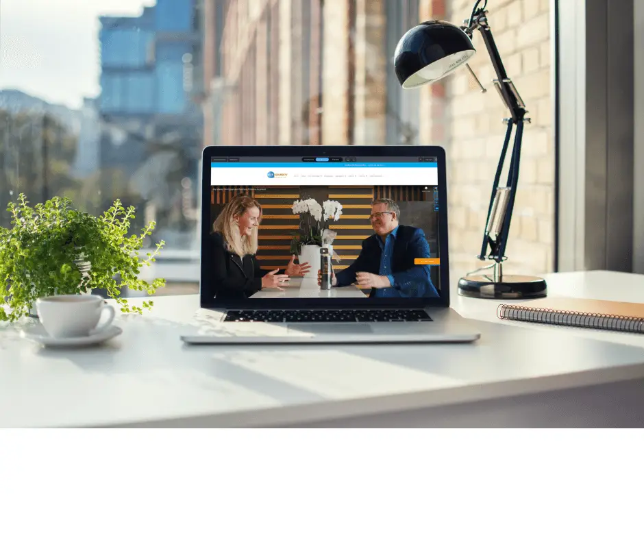 A laptop on a desk by a window